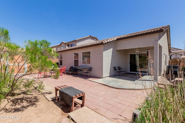 rear view of house with ceiling fan, stucco siding, a tiled roof, and a patio