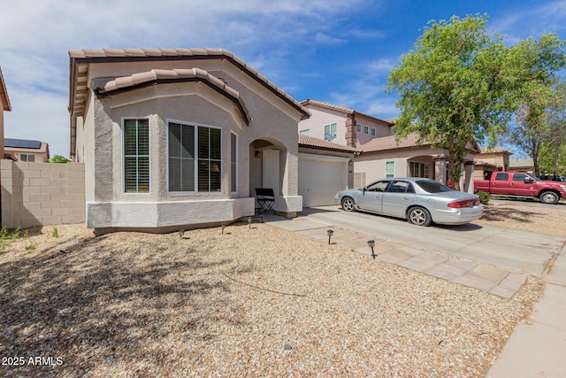 view of front of house featuring a tiled roof, concrete driveway, stucco siding, and a garage