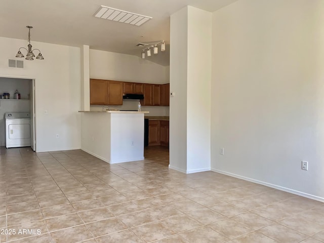 2402 E 5th St Unit 1472, Tempe, AZ 85288 - kitchen featuring washer / dryer, a chandelier, light tile patterned flooring, a peninsula, and brown cabinetry