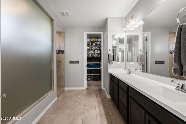 bathroom with tile patterned flooring, vanity, and walk in shower