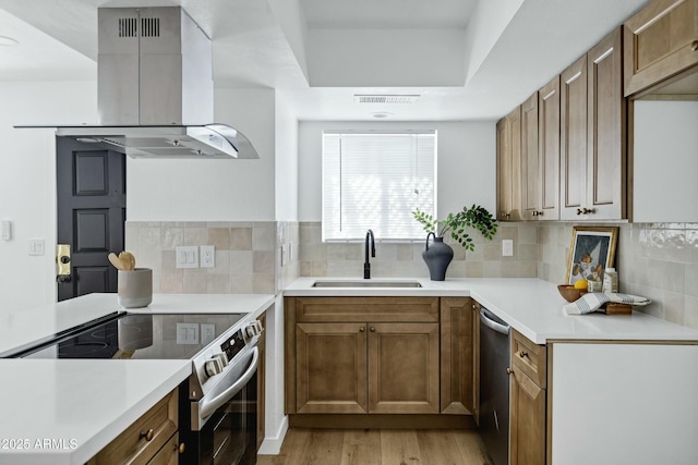 kitchen with a sink, stainless steel appliances, island exhaust hood, and light countertops