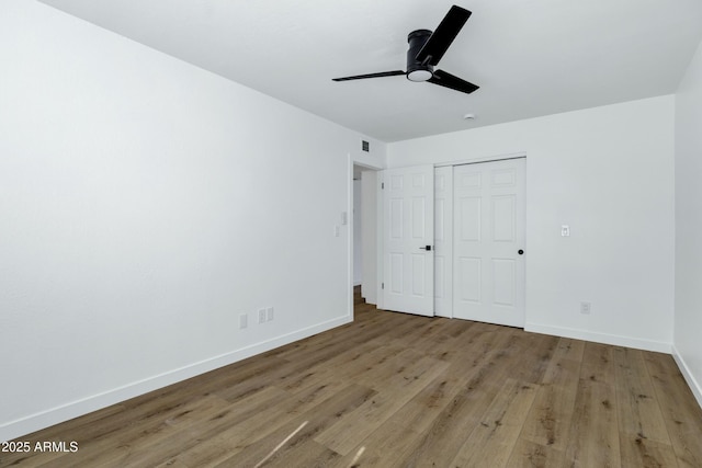 unfurnished bedroom featuring a closet, wood finished floors, visible vents, and baseboards