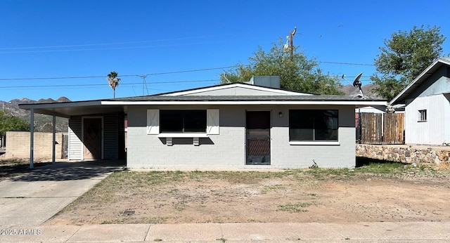 bungalow featuring concrete driveway, brick siding, fence, and a carport