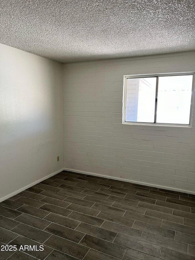 empty room featuring wood tiled floor, baseboards, and a textured ceiling