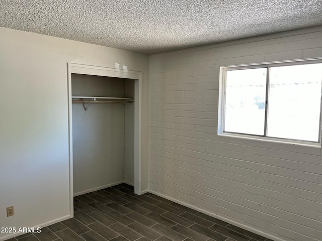unfurnished bedroom with a closet, a textured ceiling, and baseboards