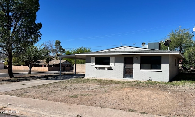 bungalow-style house featuring fence, a carport, concrete driveway, and brick siding
