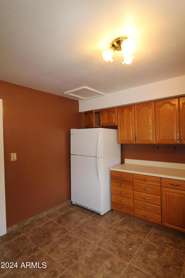 kitchen featuring dark tile patterned flooring, a textured ceiling, and white fridge