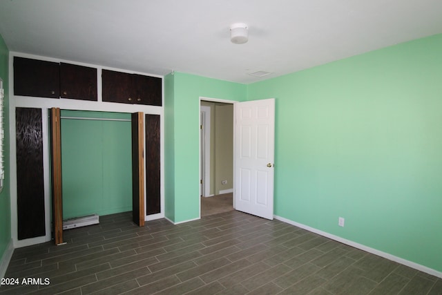 unfurnished bedroom featuring dark hardwood / wood-style floors and baseboard heating