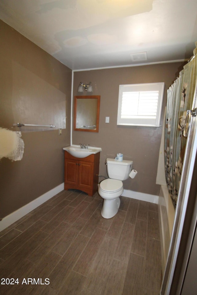 full bathroom featuring wood-type flooring, shower / tub combo, vanity, and toilet