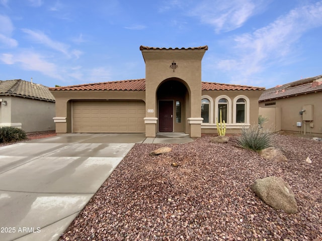 mediterranean / spanish-style home with a tile roof, stucco siding, driveway, and an attached garage