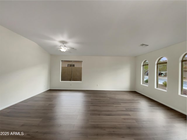 spare room with a ceiling fan, dark wood-style floors, visible vents, and baseboards