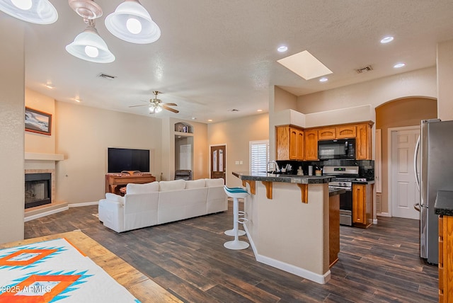 10691 E 37th Pl, Yuma, AZ 85365 - kitchen featuring a kitchen breakfast bar, brown cabinetry, a peninsula, visible vents, and appliances with stainless steel finishes