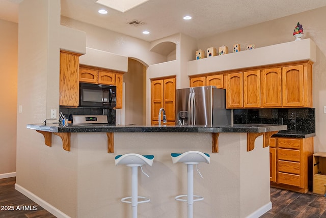 10691 E 37th Pl, Yuma, AZ 85365 - kitchen featuring tasteful backsplash, stainless steel fridge, black microwave, dark wood-type flooring, and a breakfast bar area