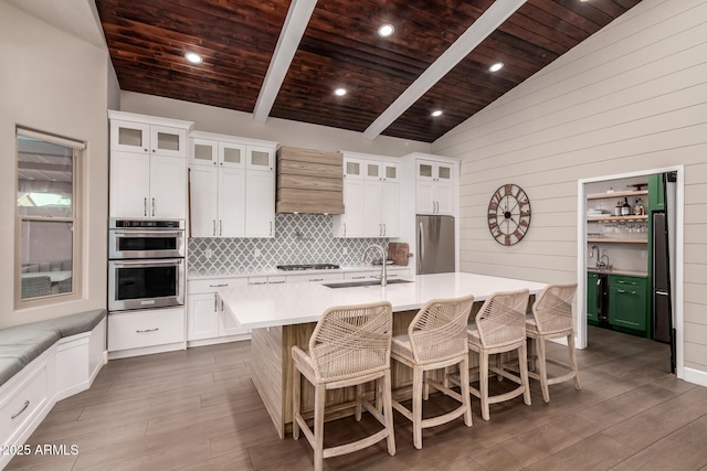 kitchen featuring appliances with stainless steel finishes, a center island with sink, and white cabinets