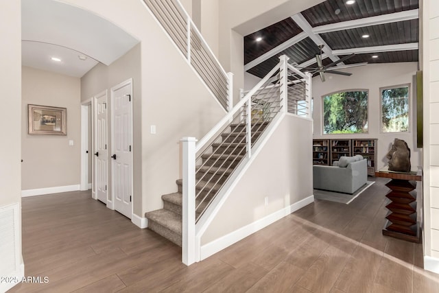 stairway featuring hardwood / wood-style flooring, lofted ceiling with beams, and ceiling fan