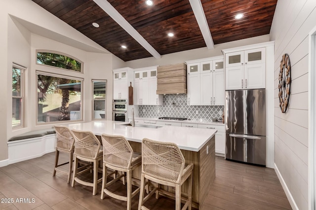 kitchen with sink, white cabinetry, wood ceiling, stainless steel appliances, and a kitchen island with sink