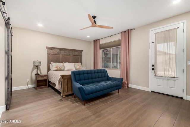 bedroom featuring ceiling fan, a barn door, and light hardwood / wood-style floors