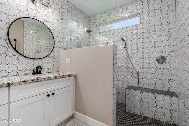 bathroom with a tile shower and vanity