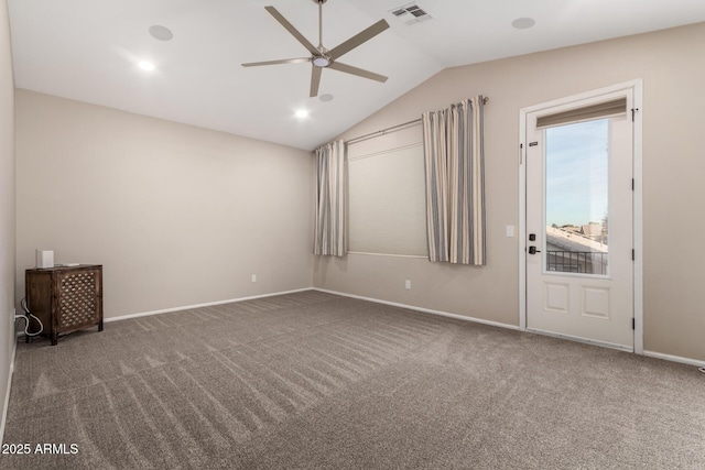 carpeted spare room featuring vaulted ceiling and ceiling fan