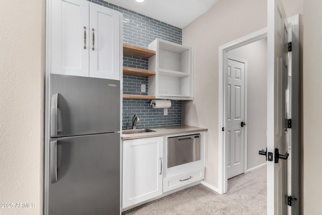 kitchen with sink, white cabinets, decorative backsplash, light colored carpet, and stainless steel appliances