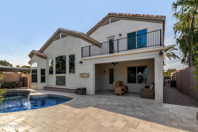 back of house featuring a fenced in pool, a patio, a balcony, and ceiling fan