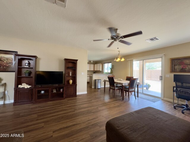 living room featuring baseboards, a ceiling fan, visible vents, and dark wood-type flooring