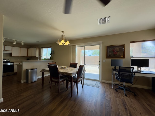 dining space featuring dark wood-style floors, a notable chandelier, visible vents, and plenty of natural light