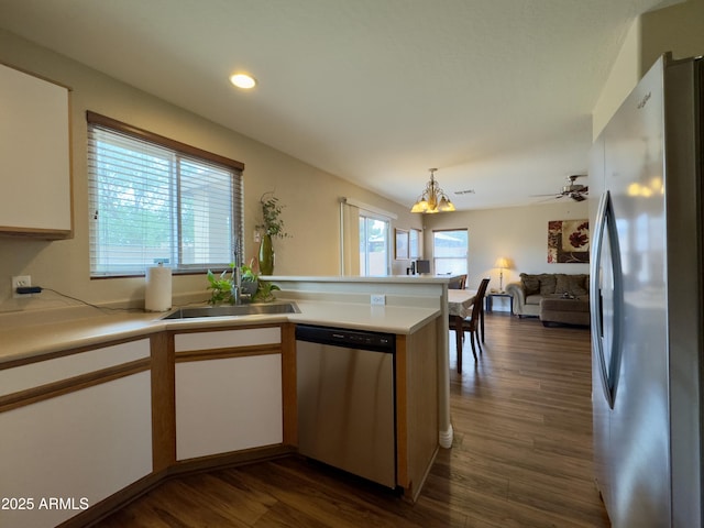 kitchen featuring stainless steel appliances, a peninsula, a sink, a notable chandelier, and light countertops
