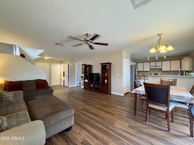 living area featuring ceiling fan with notable chandelier, visible vents, and dark wood-style floors