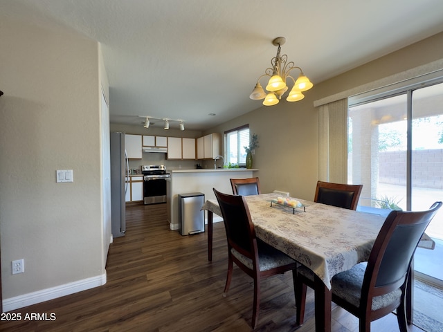 dining room featuring baseboards, rail lighting, dark wood-style floors, and a notable chandelier