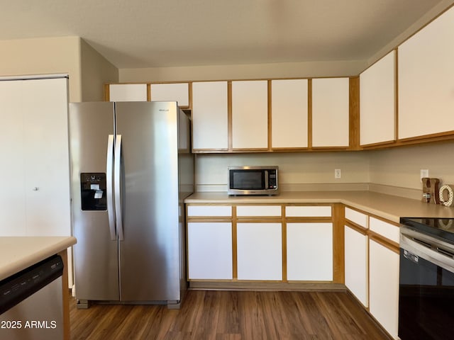kitchen with appliances with stainless steel finishes, dark wood-type flooring, white cabinetry, and light countertops