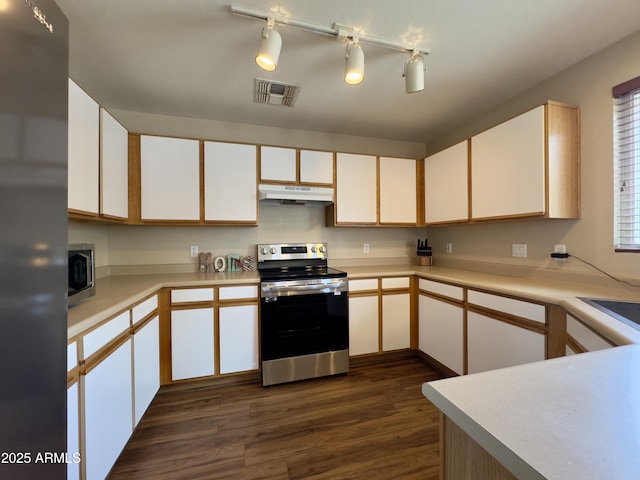 kitchen featuring appliances with stainless steel finishes, light countertops, under cabinet range hood, dark wood-type flooring, and visible vents