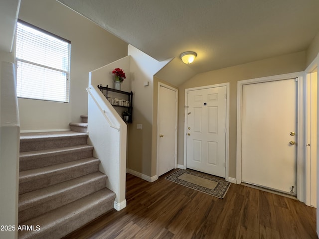 entryway featuring lofted ceiling, baseboards, wood finished floors, and stairway
