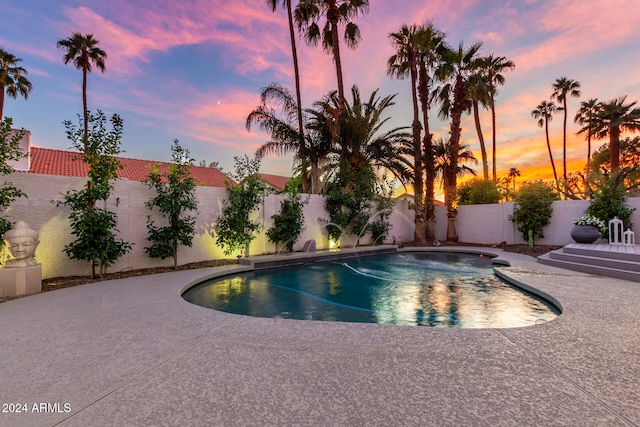 pool at dusk featuring a patio