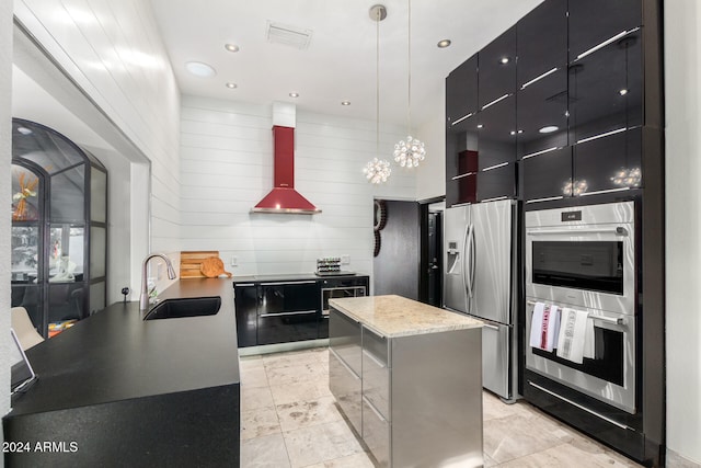 kitchen with stainless steel appliances, sink, decorative light fixtures, a kitchen island, and wall chimney range hood