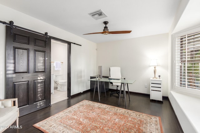 home office featuring dark wood-type flooring, a barn door, and ceiling fan