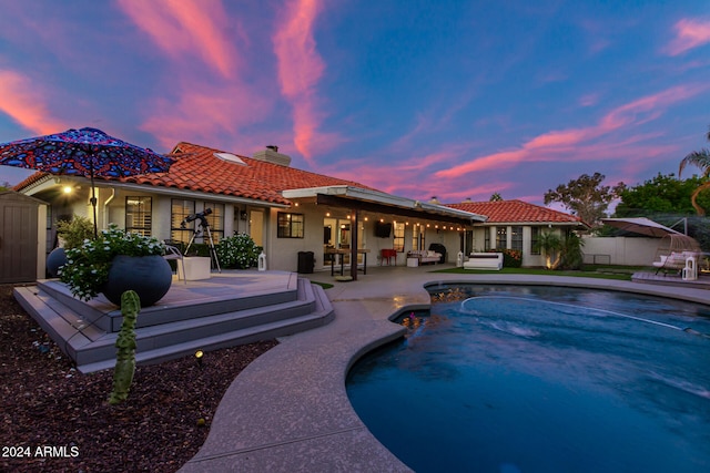 pool at dusk featuring a shed and a patio