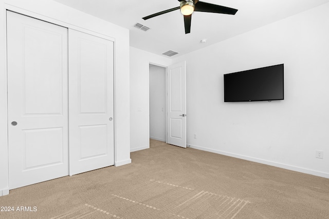 unfurnished bedroom with a closet, ceiling fan, and light colored carpet