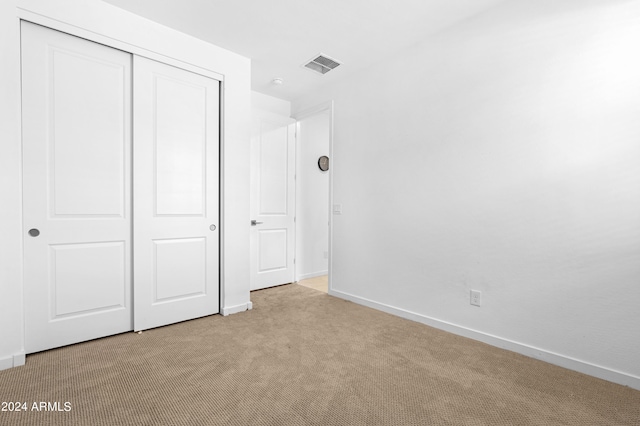 unfurnished bedroom with a closet and light colored carpet