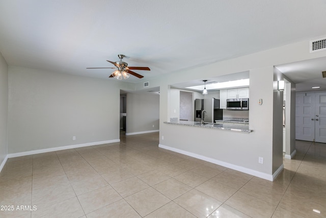 unfurnished living room featuring light tile patterned flooring, sink, and ceiling fan