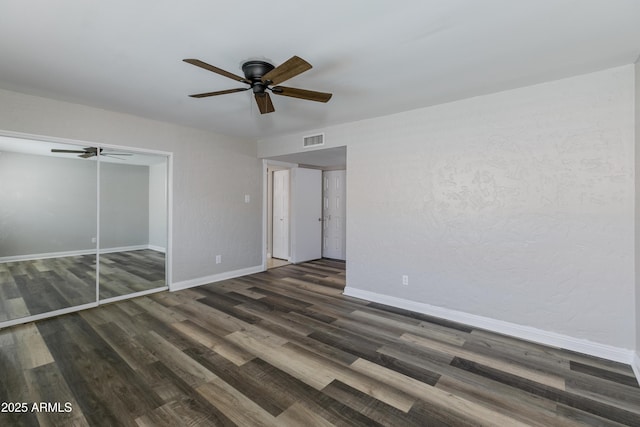 unfurnished bedroom featuring dark wood-type flooring, ceiling fan, and a closet