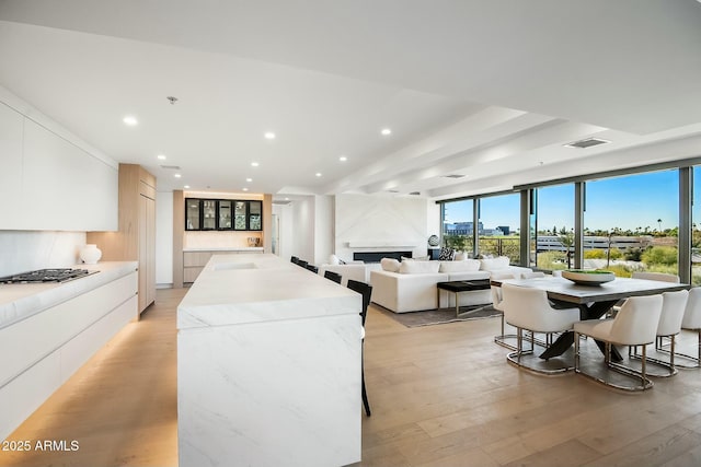 interior space with light hardwood / wood-style flooring, a breakfast bar, white cabinets, and a center island