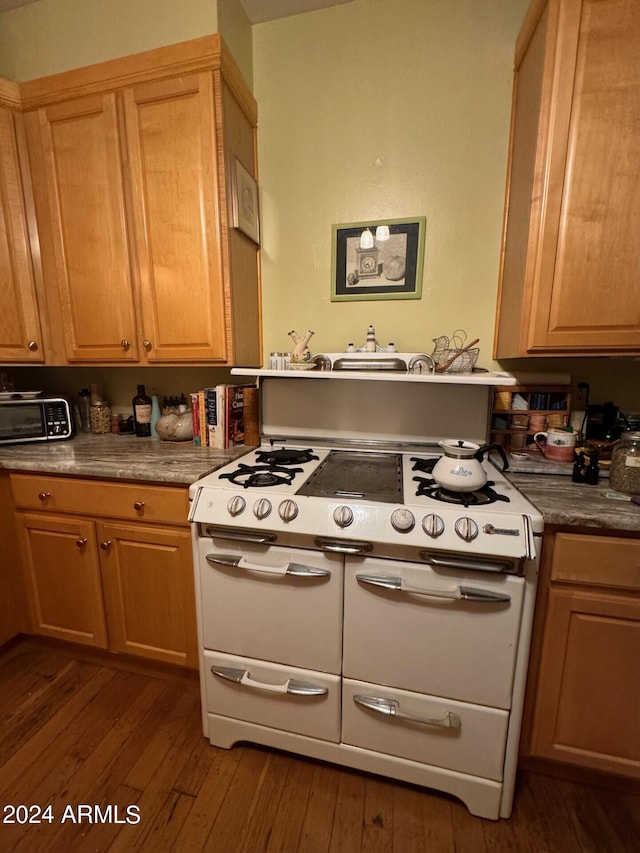 kitchen with dark hardwood / wood-style flooring, light brown cabinetry, and range with two ovens