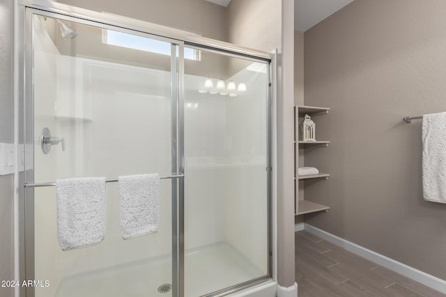 bathroom with a shower with door and hardwood / wood-style floors