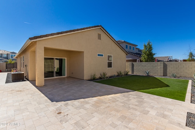 rear view of property featuring central air condition unit, a patio area, and a lawn