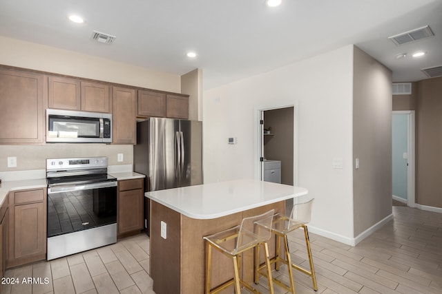 kitchen with a kitchen breakfast bar, a center island, stainless steel appliances, and light hardwood / wood-style floors