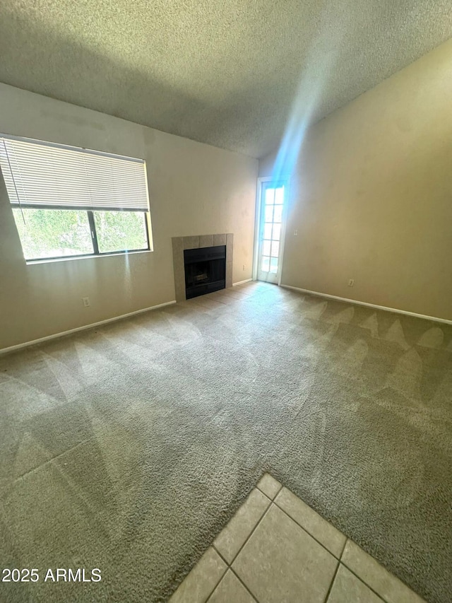 1075 E Chandler Blvd Unit 220, Chandler, AZ 85225 - unfurnished living room featuring a textured ceiling, a tile fireplace, carpet, and baseboards