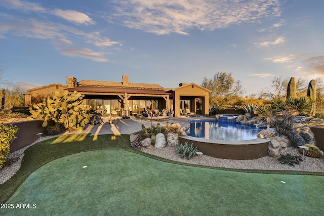 pool at dusk featuring an in ground hot tub and a patio