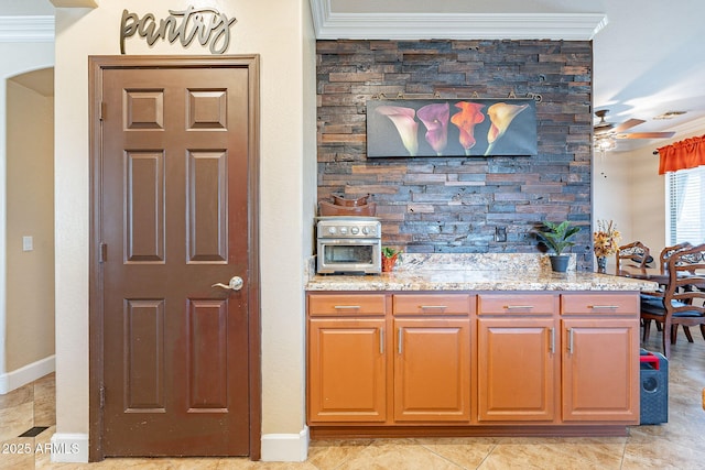 kitchen featuring crown molding, ceiling fan, and light stone countertops