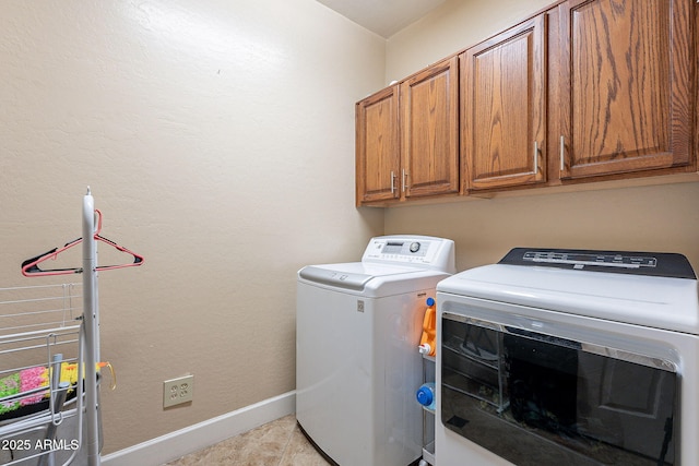 laundry room with cabinets, light tile patterned flooring, and washer and clothes dryer